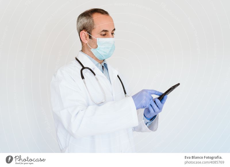 Arzt mit Schutzmaske und Handschuhen in einem Haus, der ein Mobiltelefon benutzt. Corona-Virus-Konzept Handy Technik & Technologie benutzend Internet Drahtlos