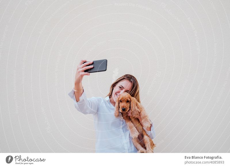 Junge Frau auf der Straße mit ihrem Cockerhund beim Fotografieren mit dem Mobiltelefon. Lifestyle im Freien mit Haustieren Handy Technik & Technologie Selfie