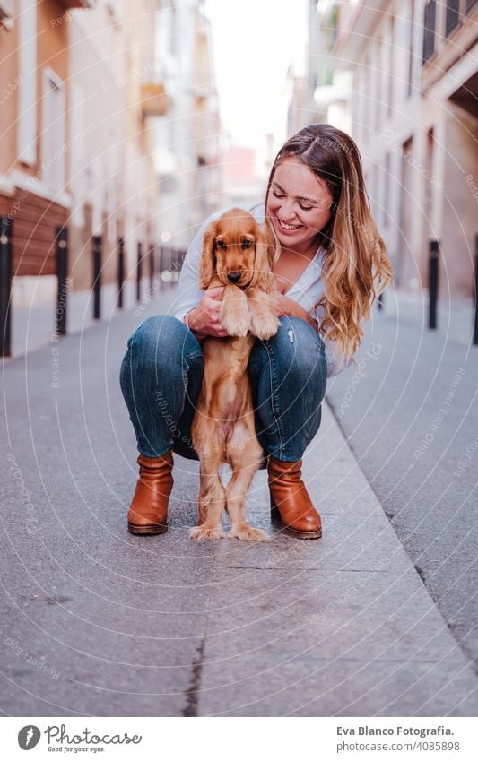 Junge Frau auf der Straße, die ihren süßen Cocker-Hund umarmt. Lifestyle im Freien mit Haustieren laufen Großstadt urban Reinrassig Kaukasier Schürhaken