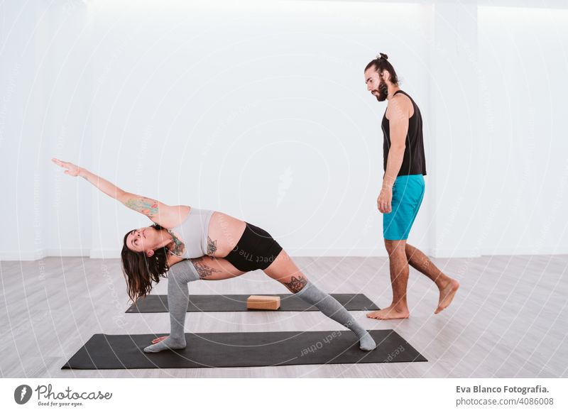 junger Mann und Frau üben Yoga-Sport in der Turnhalle. Gesunder Lebensstil Junge Gesundheit Lifestyle im Innenbereich Fitnessstudio Atelier weiß hispanisch