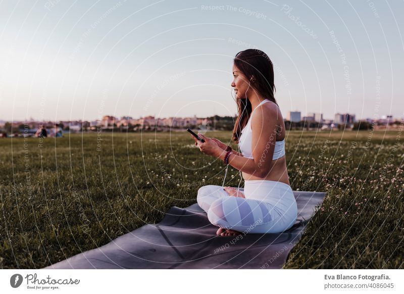 junge schöne asiatische Frau entspannt nach ihrer Yoga-Praxis Musik hören auf Kopfhörer und Handy. Yoga und gesundes Leben Konzept Sommer Glück Genuss Sport