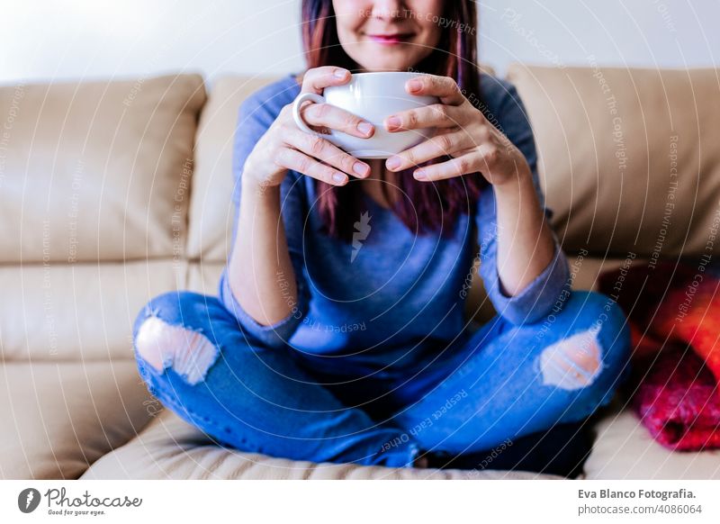 junge kaukasische Frau mit Kaffee oder Tee zum Frühstück zu Hause. Nahaufnahme lebend aussruhen Lifestyle Freizeit im Innenbereich Person Sitzen heiß Lächeln