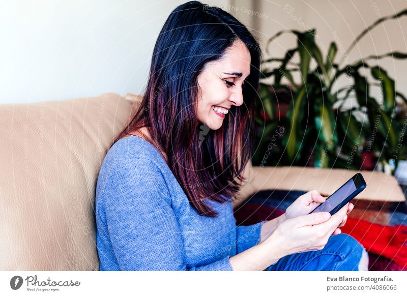 Junge Frau sitzt auf gemütlichen Sofa zu Hause und mit modernen Smartphone-Gerät, weibliche Hände tippen Textnachricht. soziale Vernetzung Konzept heimwärts