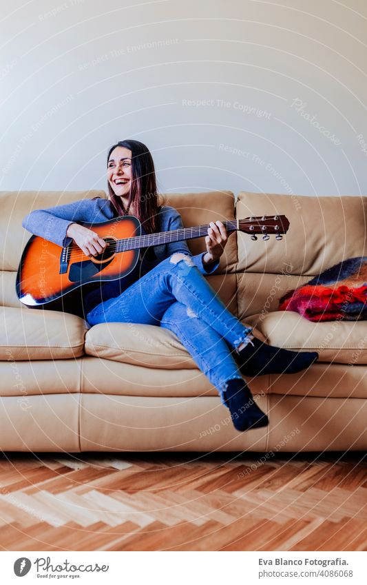 Junge schöne Frau spielt Gitarre stehend auf dem Sofa. Musik Konzept Porträt Laufwerk heimwärts Inspiration Schlafzimmer Band elektrisch Felsen Ausdruck