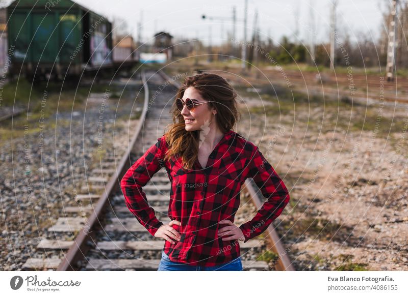 junge schöne Frau trägt lässige Kleidung, zu Fuß durch die Eisenbahn und lächelnd. Lebensstil im Freien. Reise-Konzept. Großstadt Weiblichkeit Mode attraktiv