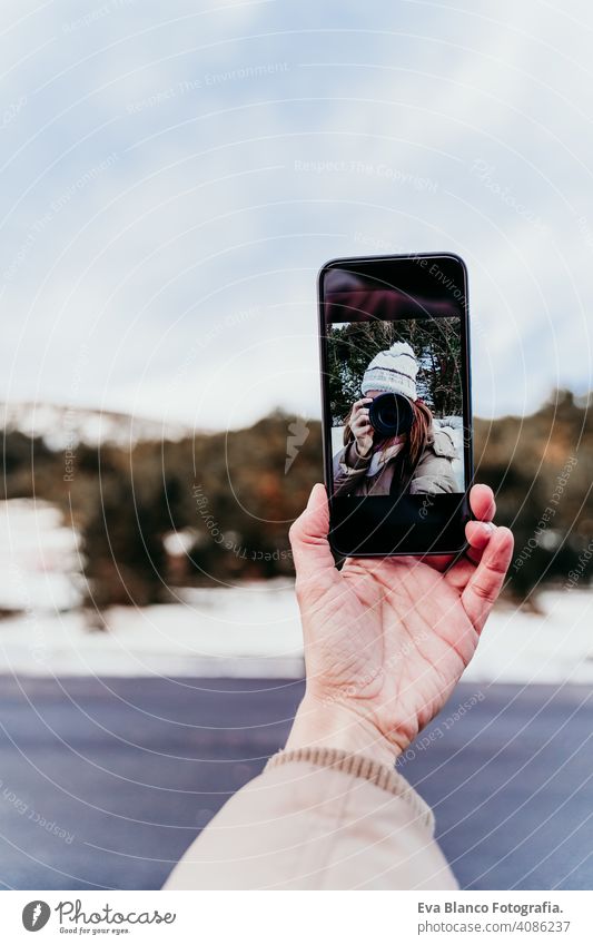 Frau auf dem Berg, die ein Selbstporträt auf dem Handy mit Kamera. Wintersaison Fotograf Fotokamera Selfie Selbstportrait Beteiligung Schnee Wald