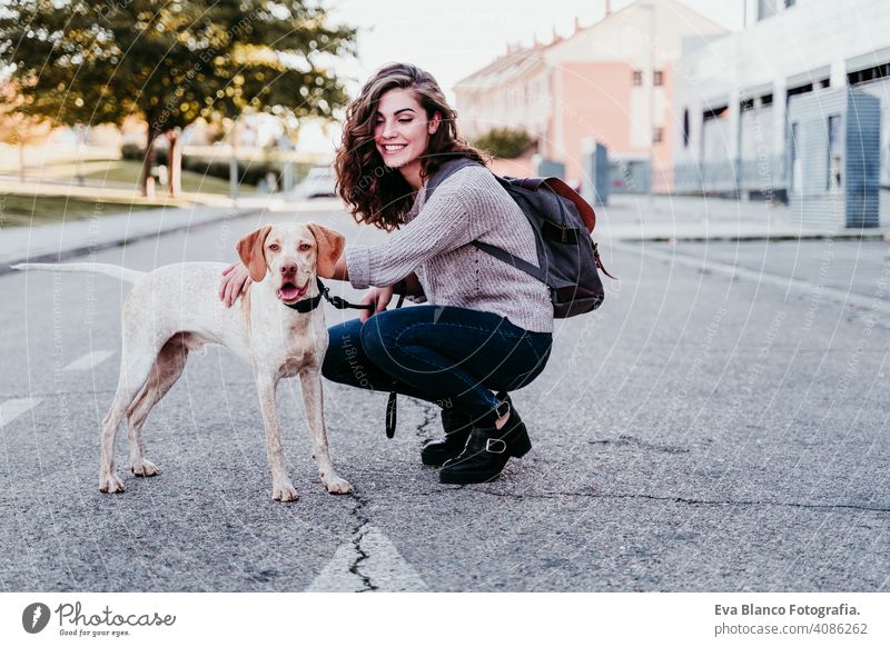 Junge Frau und ihr Hund im Freien, die an der Straße spazieren gehen. Herbstzeit Park jung Liebe Haustier Besitzer sonnig schön Glück Lächeln gemischte Rasse
