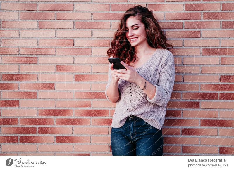 junge Frau mit Handy im Freien in der Stadt benutzend Technik & Technologie Internet Großstadt urban Wand Baustein Lächeln Glück schön brünett schreibend WiFi