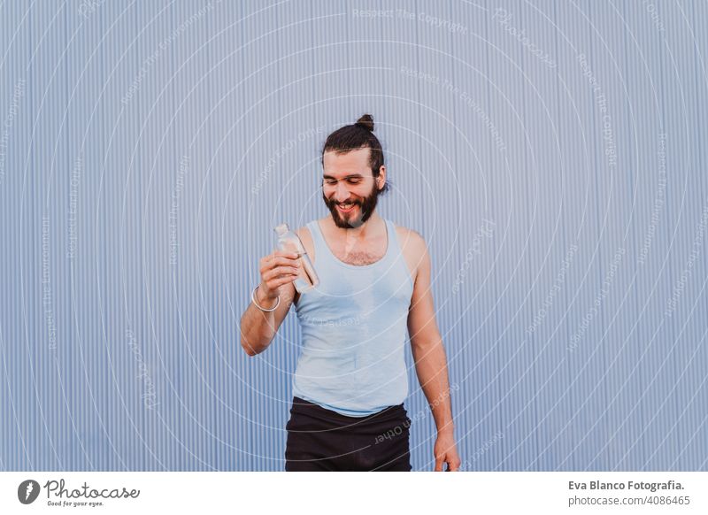 Mann in der Stadt übt Yoga Sport und Trinkwasser. blauen Hintergrund. gesunden Lebensstil Gesundheit im Freien Großstadt Blauer Hintergrund muskulös jung