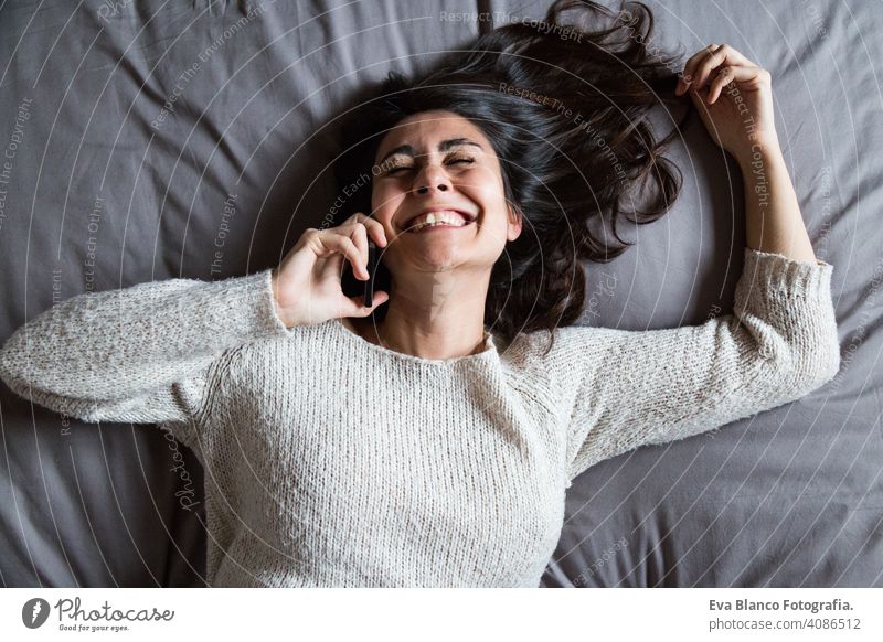 Junge Frau, die ein lustiges Gespräch am Telefon führt jung Kaffee Lifestyle lässig Internet Business Vernetzung Selfie sozial Bett Haus heimwärts Schlafzimmer