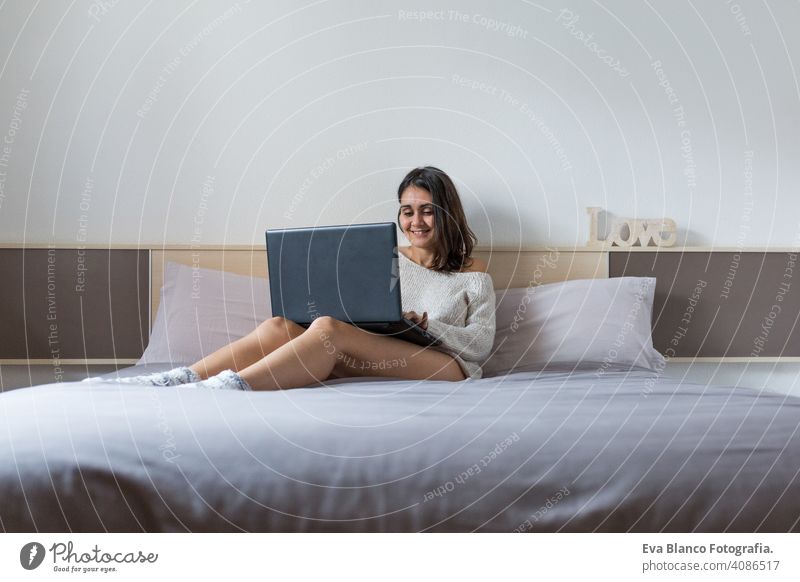 Junge Frau sitzt auf dem Bett und arbeitet mit Laptop jung Kaffee Lifestyle Computer Tasse lässig Internet Business Vernetzung arbeiten Tippen sozial Haus