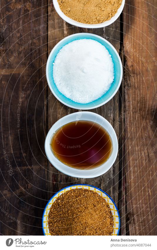 Verschiedene Arten von Zucker und Süßstoffen in den Schalen Demerara Ahornsirup Liebling Kokosnuss Agave Zuckerguß Nachlauf granuliert golden Rohr Dessert braun