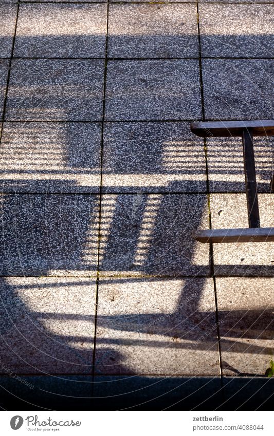 Schatten von Klappstühlen auf der Terrasse licht sonne schatten stuhl klappstuhl gartenstuhl möbel gartenmöbel kleingarten schrebergarten terrasse fuge platte