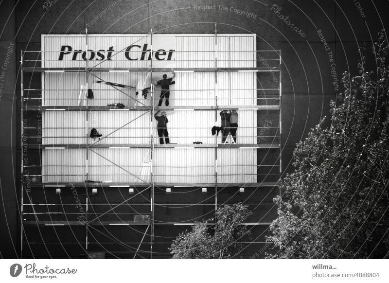 Plakatkleber auf einem Gerüst amaPlattenbau - Prost Cher Hauswand Plakatwand plakatieren Werbung Menschen Männer
