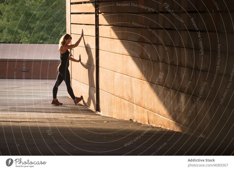 junge Frau, die sich an eine Straßenmauer lehnt strecken Beine rennen Fitness Training Lifestyle Gesundheit Sport Athlet passen Übung Menschen Sportbekleidung