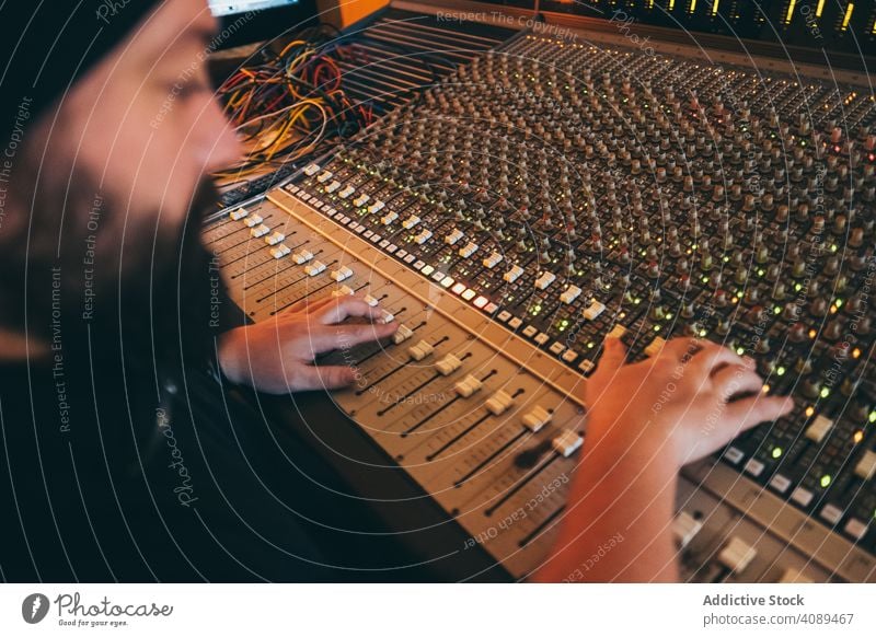Mann an einem Equalizer-Instrument in einem Studio Spielen akustisch Musiker spielen Klang Einsteller Resonanzboden Inszenierung Knöpfe Radio Komponist Atelier