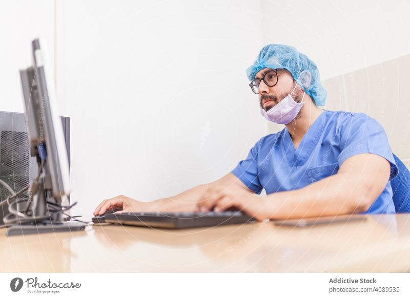 männlich Chirurgie am Computer arbeiten vor der Operation Erwachsener Krankenhaus medizinisch benutzend Kaukasier Arzt Medizin Büro Uniform Mantel Personal