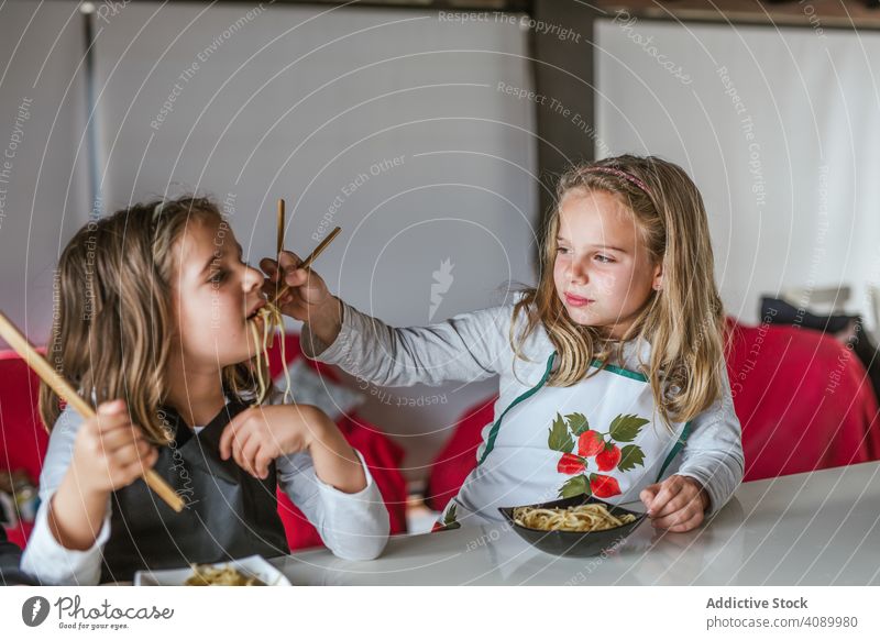 Kinder essen zu Hause veganes Essen Veganer Lebensmittel Nudeln Küche heimwärts Sitzen Tisch Zusammensein Essstäbchen Geschwister Schnitzel Gemüse Portion