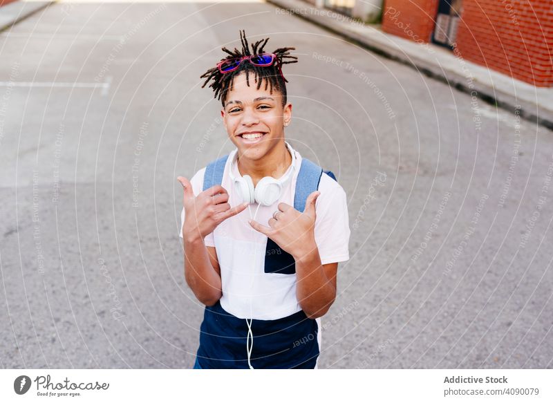 Junge fröhliche schwarze Männchen stehen auf der Straße Mann Glück Großstadt Kopfhörer Shaka-Zeichen Hipster jung Afroamerikaner männlich ethnisch Lächeln
