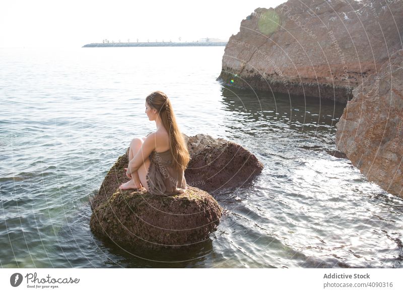 Barfuß Frau sitzt auf einem Felsen und schaut auf das Meer Sitzen MEER jung Gewebe Wind Wasser Felsbrocken Urlaub reisen Ausflug Tourismus sinnlich elegant