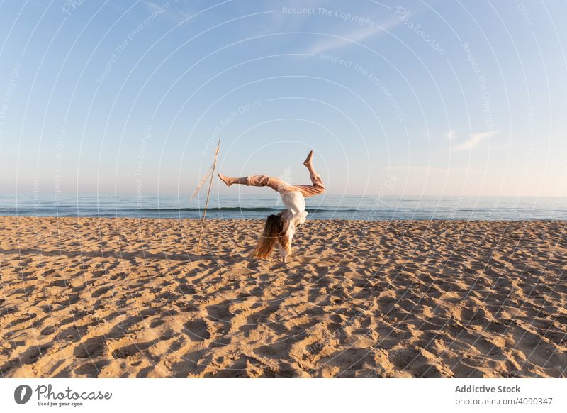 Teenager-Mädchen mit Stock und Bänder am Strand tun Handstand kleben Lächeln Wegsehen Lifestyle Freizeit Natur lange Haare Spaß Himmel wolkenlos ruhen