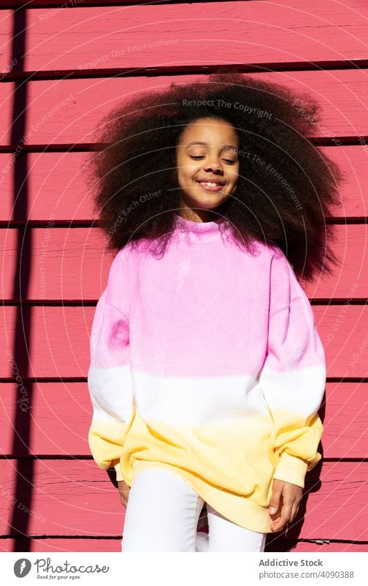 Lächelndes Mädchen steht in der Nähe von rosa Wand trendy Stehen Afroamerikaner Glück schön hübsch heiter attraktiv niedlich Menschen Fröhlichkeit Freude