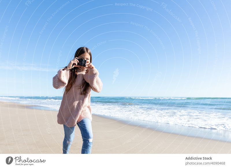 Lächelndes Mädchen nimmt Fotos am Strand Fotoapparat MEER sonnig tagsüber Sand wolkenlos Himmel Lifestyle Freizeit Hobby Kind Teenager Glück Wochenende