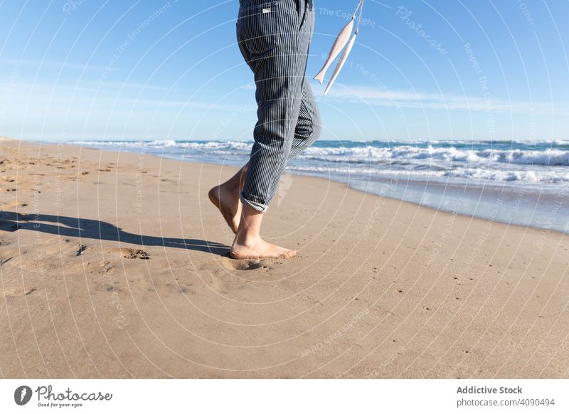 Lächelndes Mädchen hält Bänder am Strand MEER Accessoire Barfuß Sand zeigend Wellen sonnig Tourismus Urlaub tagsüber Kind Teenager Meer Wasser demonstrierend