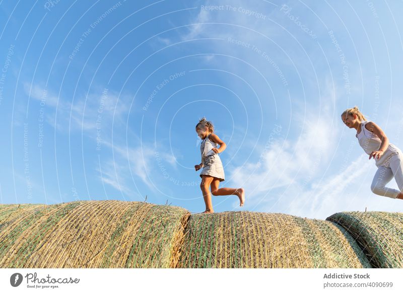 Geschwister laufen auf Heuhaufen rennen Bauernhof Himmel Wolken sonnig tagsüber Natur Zusammensein Junge Mädchen Lifestyle Freizeit Familie Schwestern Bruder