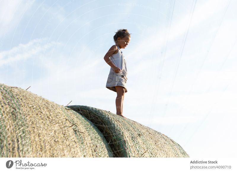 Barfuß Mädchen stehen auf Heuhaufen Bauernhof Himmel Wolken sonnig tagsüber Natur Lifestyle Freizeit Teenager Kind getrocknet Gras Stroh Brötchen Landschaft