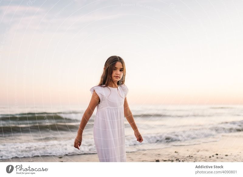 Adorable Mädchen zu Fuß und Blick auf die Kamera am Meer bei Sonnenuntergang Seeküste laufen bezaubernd Meeresufer Sonnenschein Strand Sommer Wasser MEER sonnig