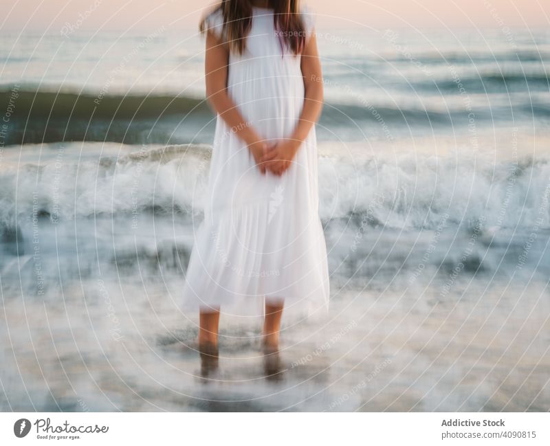 Unscharfes Mädchen am Meer zwischen Wellen stehend Porträt Seeküste winken Lächeln charmant Wasser Strand bezaubernd Stehen Sommer schön Frau Kind Kindheit