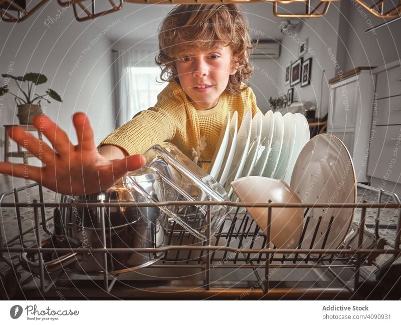 Junge in der Nähe der offenen Spülmaschine Küche Routine Geschirrspüler Hausarbeit heimwärts geschlossene Augen Kind gewelltes Haar Pyjama Küchengeräte