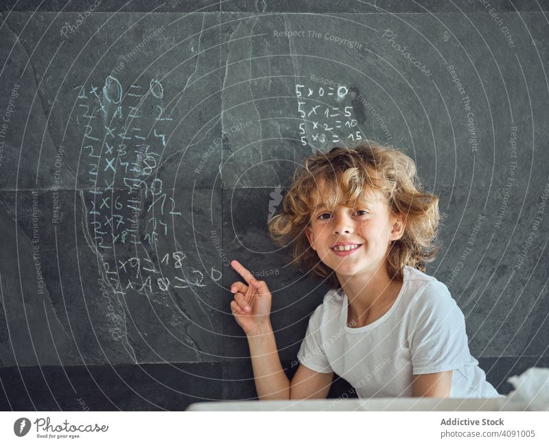 Kind zeigt auf Multiplikationstabelle an der Wand Tisch zeigend Lächeln Bildung lernen Mathematik elementar Wissen schreiben Lektion Kreide Kindheit lehren