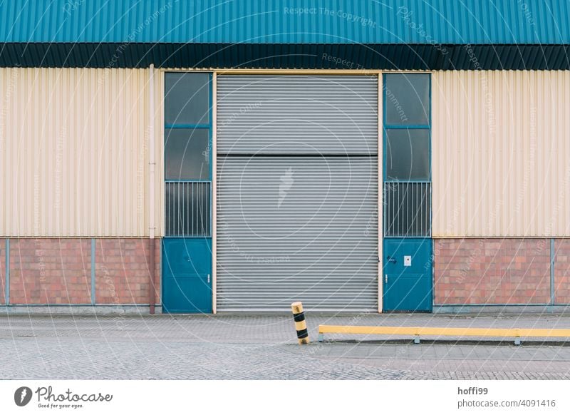 triste Ansicht einer Lagerhalle mit angefahrenen Begrenzungspfahl Hafen Fassade Lagerhaus Wand Industrieanlage Fabrik Architektur Handel Industriefotografie
