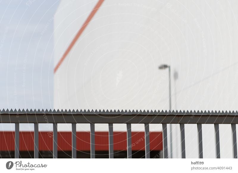 Nahaufnahme eines Gitterzaum mit Sägezahnkrone das ein industrielles Gebäude abriegelt Zaun abgeriegelt bewacht Schutz abschirmen bewachen Barriere Metall Stahl