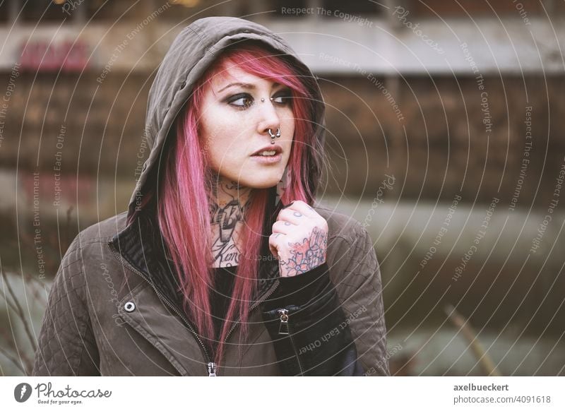 junge Frau mit pinken Haaren, Piercings und Tattoos echte Menschen Junge Frau E-Girl Hipster Subkultur pinke haare gepierct tätowiert alternativ Parka Emo