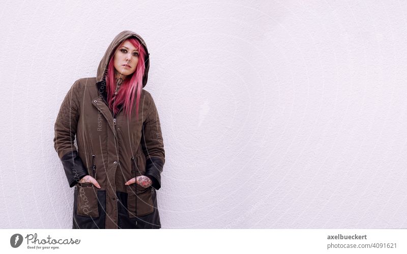 junge Frau mit pinken Haaren, Piercings und Tattoos Junge Frau E-Girl Hipster echte Menschen Subkultur pinke haare gepierct tätowiert alternativ Parka Emo