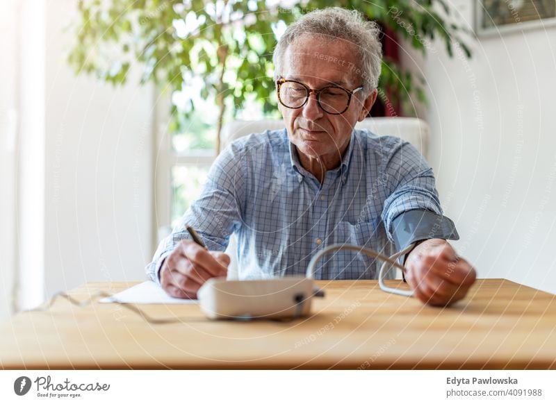 Älterer Mann verwendet medizinisches Gerät zur Blutdruckmessung Senior älter Großvater alt Rentnerin in den Ruhestand getreten gealtert reif heimwärts Haus