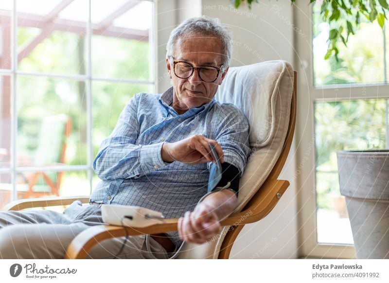 Älterer Mann verwendet medizinisches Gerät zur Blutdruckmessung Senior älter Großvater alt Rentnerin in den Ruhestand getreten gealtert reif heimwärts Haus