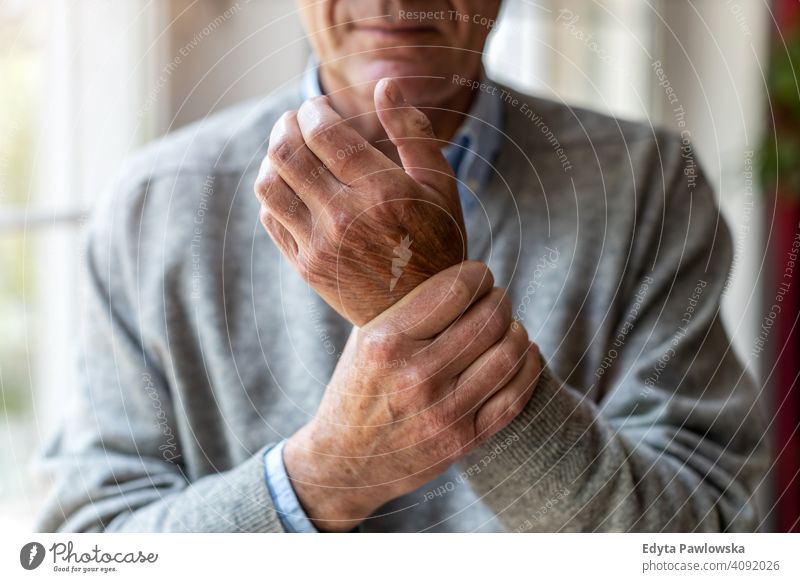 Älterer Mann mit Arthritis reibt sich die Hände Rheumatismus steif Verbindungen steife Gelenke massierend Handgelenk Osteoporose berührend Reibung Verletzung
