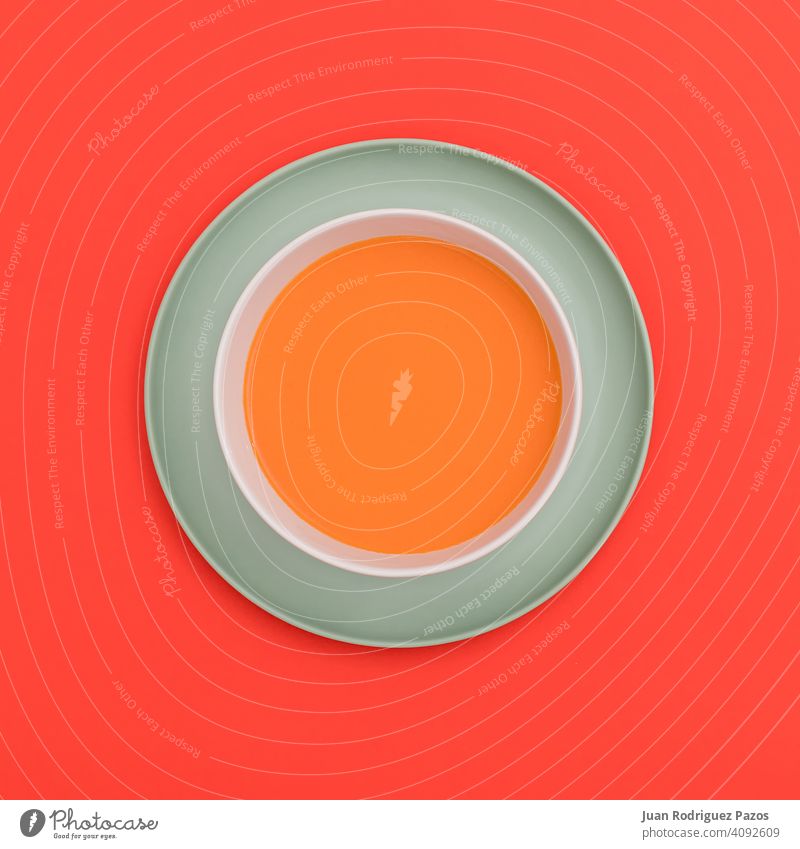 Gazpacho-Schale auf einem blauen Teller und rotem Hintergrund. Ansicht von oben. farbenfroh kreativ lecker Diät Speise trinken frisch Geometrie Gesundheitswesen