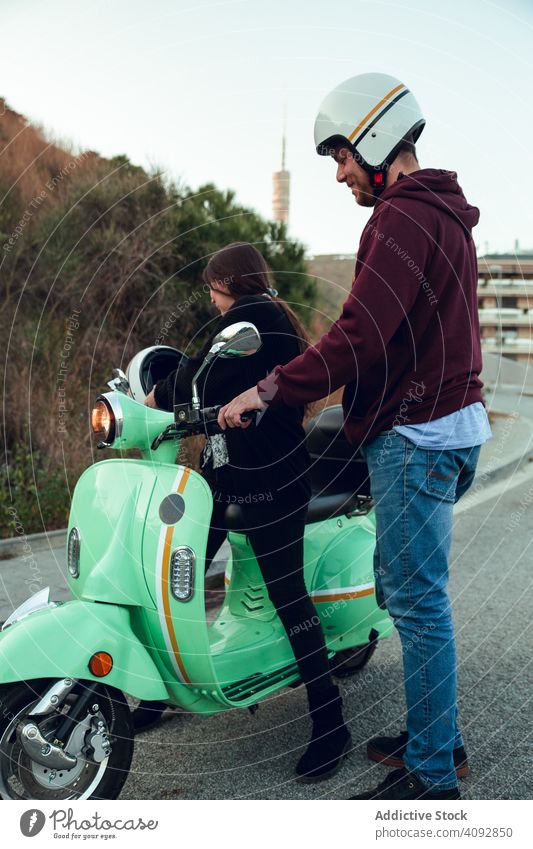 Mann hilft Frau sitzen auf Fahrrad Schutzhelm Freundschaft Tretroller Aktivität Freizeit Straße Abenteuer Motorrad reisen genießend Transport Verkehr jung