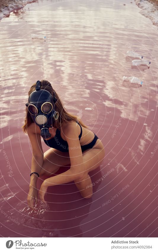 Weiblich in Badekleidung zu Fuß in schmutzigen Pool mit Wurf Verschmutzung Wasser See Kunststoff Flasche Atemschutzgerät Frau Abfall dreckig Badebekleidung