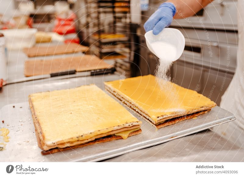 Crop Konditor verschüttet Zucker auf Kuchen Bäckerei Gebäck verschütten schaufeln Lebensmittel süß Pulver Qualität Kleinunternehmen Industrie Vorbereitung