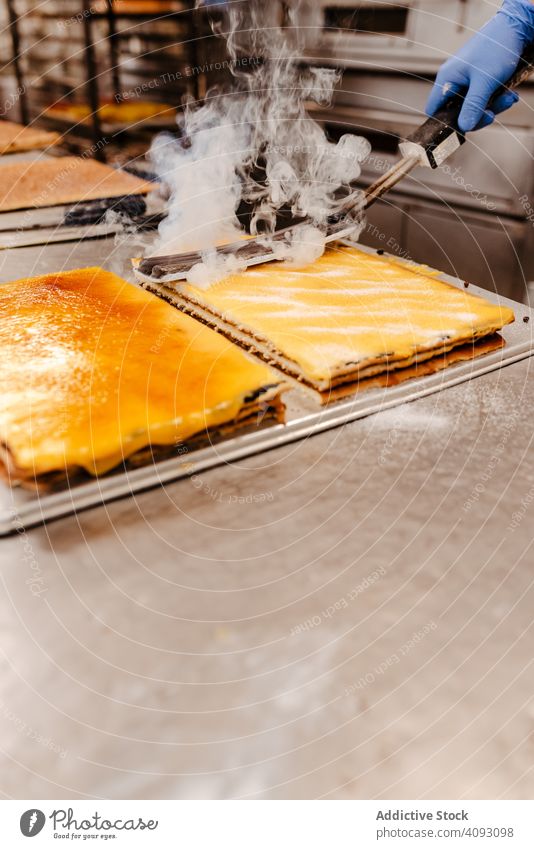 Crop Konditor verschüttet Zucker auf Kuchen Bäckerei Gebäck verschütten schaufeln Lebensmittel süß Pulver Qualität Kleinunternehmen Industrie Vorbereitung