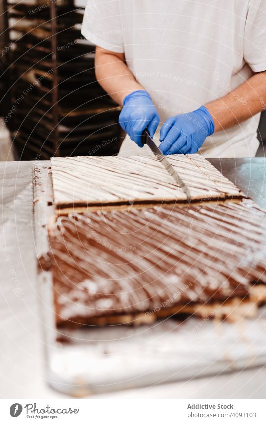 Anonymer Koch schneidet Kuchen auf dem Tisch an Konditor Bäckerei geschnitten Messer Gebäck süß frisch Küche Lebensmittel Vorbereitung Kleinunternehmen Mann