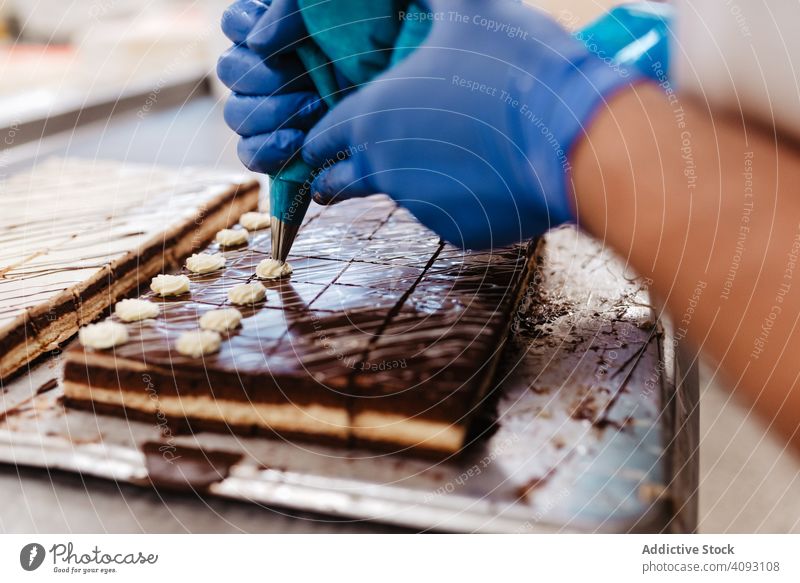 Getreide-Konditor, der kleine Kuchen dekoriert Bäckerei Sahne drücken Schokolade Tablett Koch Gebäck Lebensmittel frisch Qualität Vorbereitung Arbeit