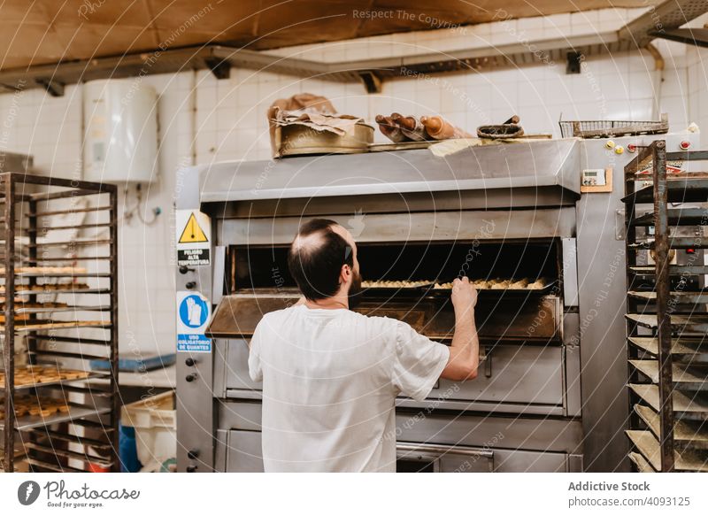 Kahlköpfiger Bäcker prüft Gebäck im Ofen Mann Bäckerei schauen Sie Arbeit Konditor prüfen Koch heiß Prozess männlich Erwachsener Uniform Küche Kleinunternehmen
