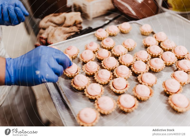 Anonymer Bäcker beim Dekorieren kleiner Kuchen Konditor Bäckerei Gebäck Arbeit Qualität Lebensmittel traditionell Mann Vorbereitung Inszenierung